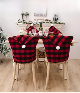 Detail of red and black buffalo plaid Christmas hat chair covers with white pom poms