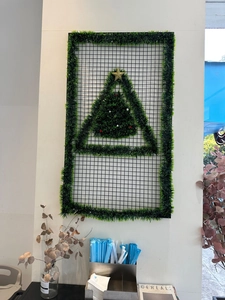 Wall-mounted metal grid Christmas tree decor with green tinsel and gold star details