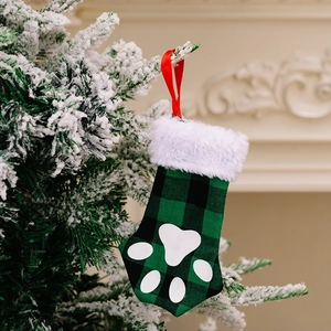 Detail of green plaid pet paw Christmas stocking hanging on a festive decorated tree