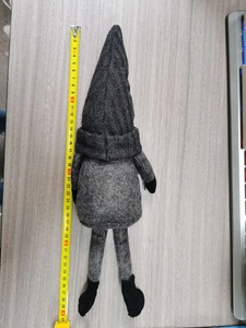 Macro detail of a 40cm tall grey knitted Christmas gnome doll with long legs for decor
