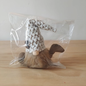 Detail view of gnome plush doll with knitted hat and brown beard in clear packaging