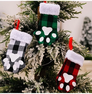 Trois chaussettes de Noël à carreaux avec empreintes de pattes sur un sapin festif