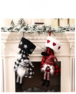 Close-up of red and black plaid Christmas stockings with cute plush elves on a fireplace