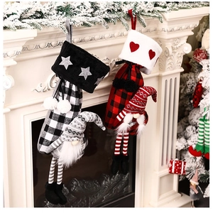 Detail of buffalo plaid Christmas stockings with faceless gnomes hanging on a white fireplace