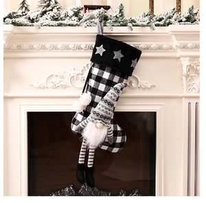 Close-up of a Christmas stocking with gnome and black white plaid on a white fireplace