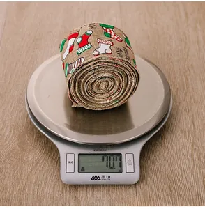 Detailed view of burlap Christmas ribbon roll with red and green sock prints on weighing scale