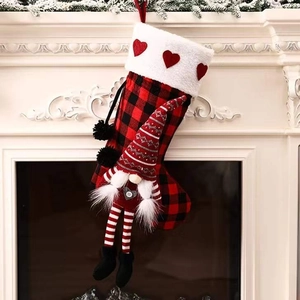 Red and black buffalo plaid Christmas stocking with cute gnome hanging on fireplace