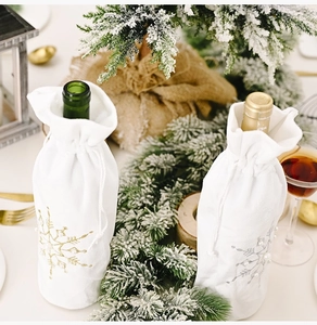 Detail of white velvet wine bottle covers with embroidered snowflakes for Christmas decor
