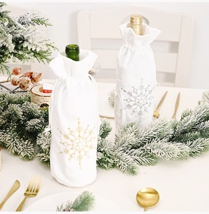 Detail of white Christmas wine bottle bags with gold and silver snowflake embroidery