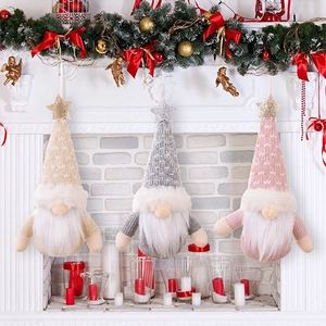 Three knit Christmas gnome ornaments with glitter stars hanging from a festive white mantel