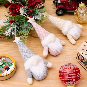 Three knitted Christmas gnome ornaments with glitter stars in a warm festive holiday setting