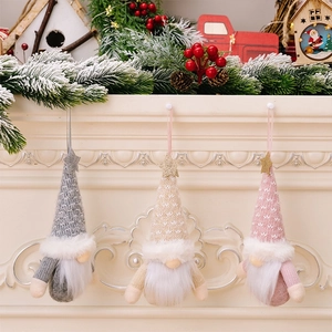 Close-up of three knitted Christmas gnomes hanging on a festive decorated white fireplace