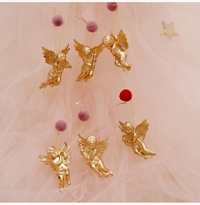 Detailed macro shot of six golden Christmas angel ornaments with instruments and pom-poms