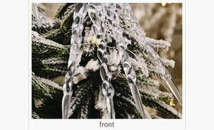 Close-up of clear spiral icicle ornaments hanging on a snowy Christmas tree branch