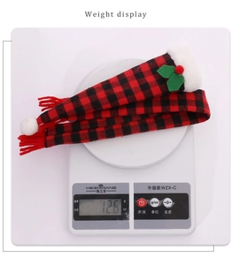 Close-up of a Christmas plaid wine bottle scarf with red tassels and green leaf berry accents