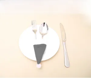 Close-up of gray felt Christmas hat cutlery holder set on a white dinner plate