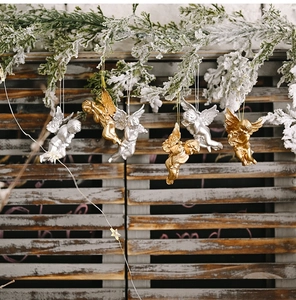 Vintage gold and silver angel ornaments hanging on snow-covered Christmas tree branches
