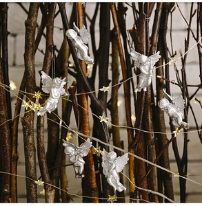Detailed view of silver angel ornaments hanging on branches with warm starry lights