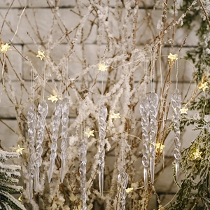 Set of transparent spiral icicle ornaments hanging on snow-covered branches