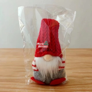 Detail view of a Christmas gnome plush with red knit hat and Merry Christmas text