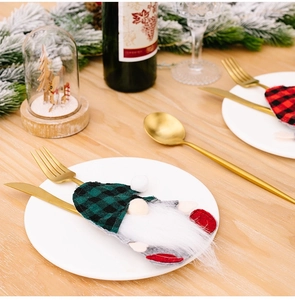 Close-up of Christmas gnome cutlery holder with red plaid hat on a white dinner plate