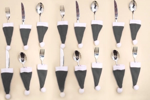 Detailed view of 16 grey and white Christmas hat cutlery holders with metal forks