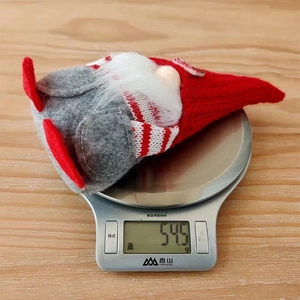 Detailed view of a red Christmas gnome on a digital scale showing weight of 54.5g