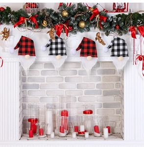Christmas gnome ornaments with red black plaid hats hanging on a white fireplace mantle