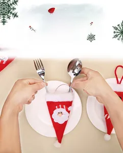 Détail d'un porte-couverts en bonnet de Noël sur une assiette blanche avec couverts