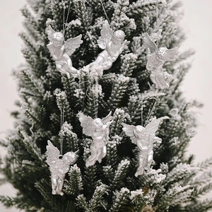 Set of 6 silver Christmas angel figurines hanging on a frosted pine tree branch