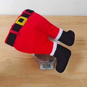 Vue détaillée du chapeau pantalon de Noël en peluche pesé sur une balance numérique