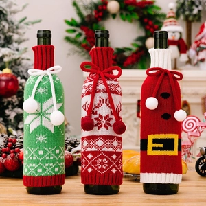 Detailed view of three knitted Christmas wine bottle covers with snowflakes and reindeer