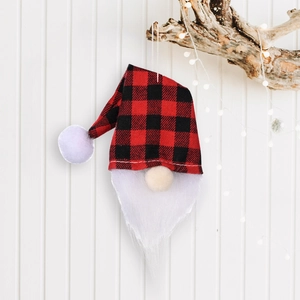 Christmas gnome ornament with red black plaid hat and white fur beard on festive wood background