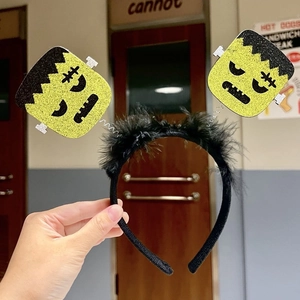 Close-up of Halloween headband featuring green glitter Frankenstein heads on springs