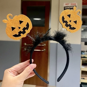 Detail of Halloween headband with glitter gold pumpkins, black feathers and springs