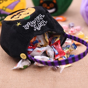 Detail of plush black Halloween pumpkin candy bag with striped handle and embroidery