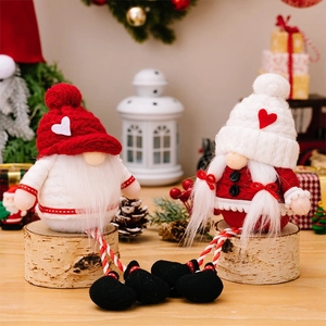Close-up of handmade Christmas gnomes with long striped legs sitting on wooden stumps