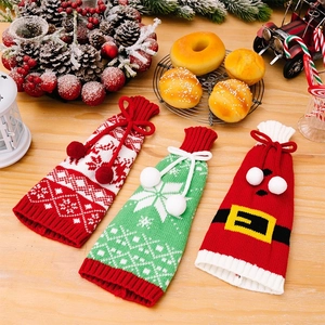 Detailed view of three knitted Christmas wine bottle covers with snowflakes and Santa designs