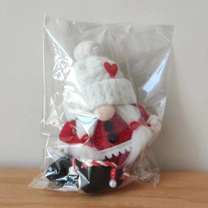 Close-up of a Christmas gnome with white knitted heart hat in transparent packaging