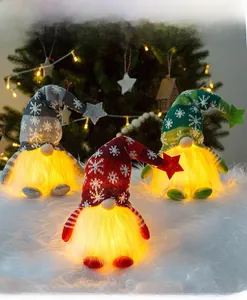 Three glowing Christmas gnomes with knitted snowflake hats on a white plush rug