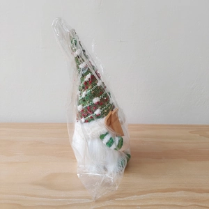 Detail of Christmas gnome with knit hat and wooden skis inside transparent packaging