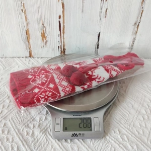 Detail of red and white knitted Christmas wine bottle cover packaging on a digital scale
