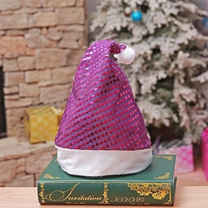 Detail of purple sequin Christmas hat with plush trim on vintage book by fireplace