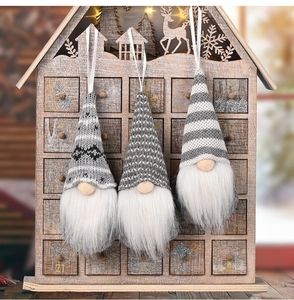 Detailed view of three knitted Christmas gnomes with white ribbons for hanging decorations