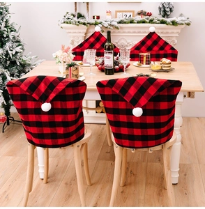 Detail of red and black buffalo plaid Christmas chair covers with white pom-poms