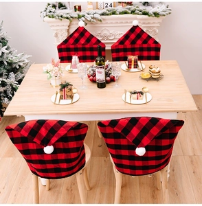 Detail of red and black buffalo plaid Christmas hat chair covers with white pom poms