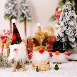 Drei beleuchtete Weihnachtswichtel mit Rentierhut und Karomuster in einer Winterlandschaft