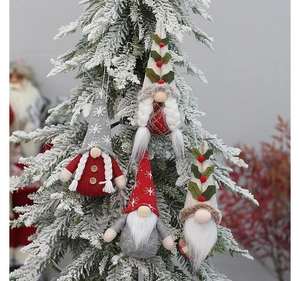 Detailed view of handmade Christmas gnomes with knit hats hanging on a snowy festive tree