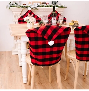 Detail of red and black buffalo plaid Christmas chair covers with white pom-pom toppers