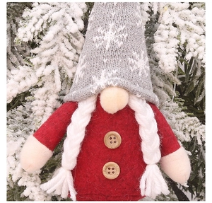 Close-up of a Christmas gnome with grey snowflake hat and red felt body with wooden buttons